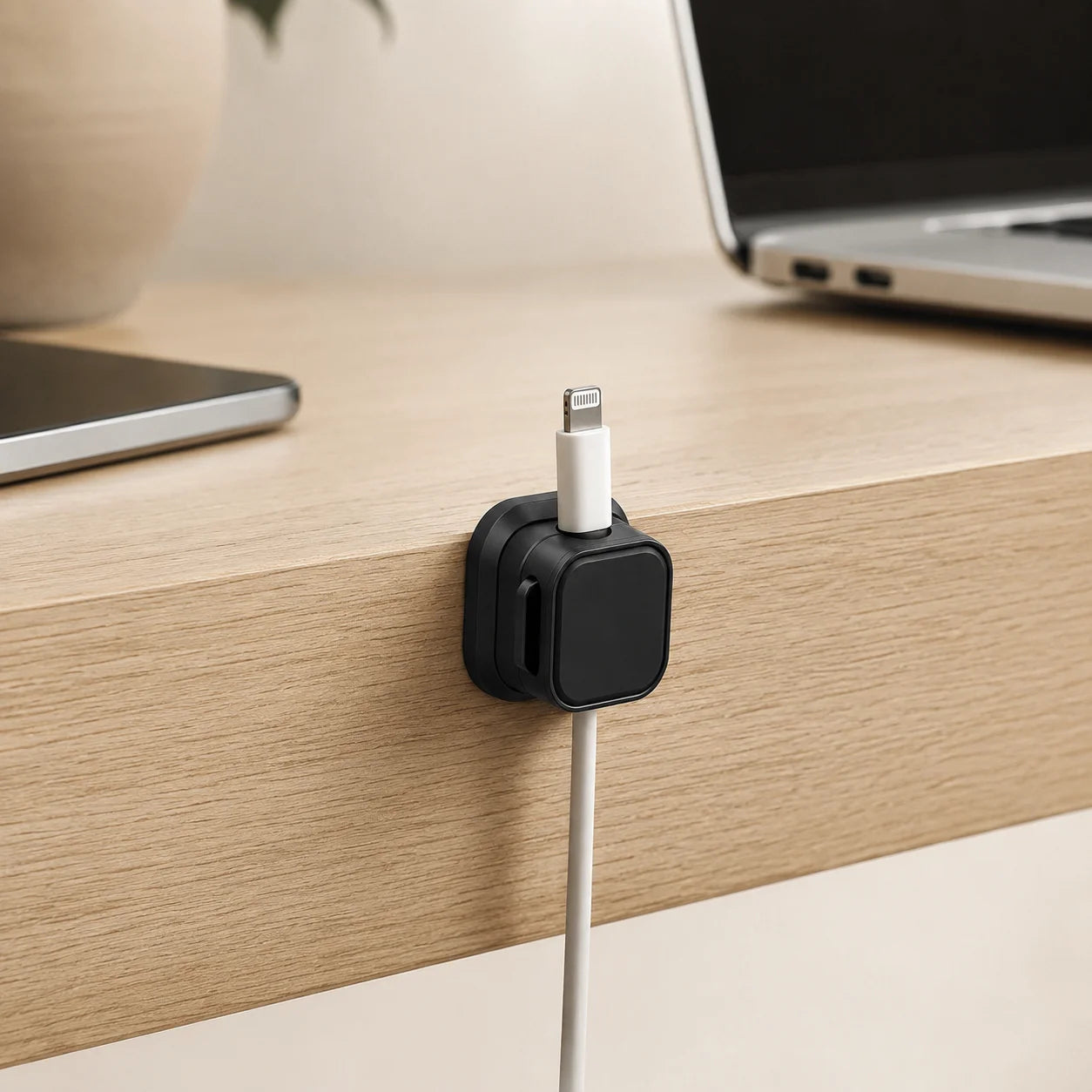 CableRest, Anwendungsszene, schwarzer Kunststoff, weißes Ladekabel an Schreibtischkante aus Holz fixiert