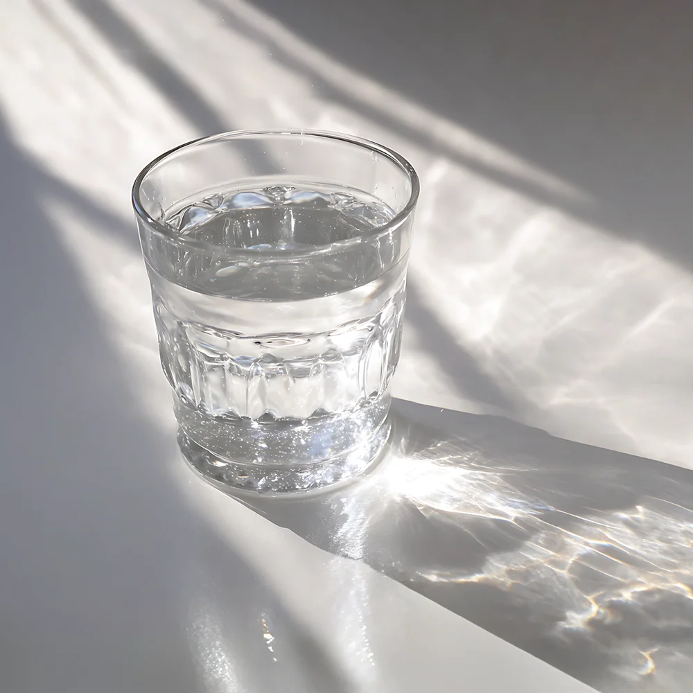 glas wasser auf heller fläche, weiches licht