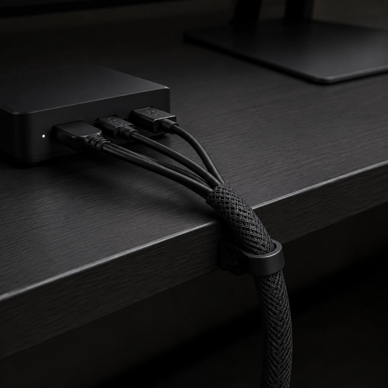 LineSleeve, Anwendungsdetail am dunklen Schreibtisch, Schwarz, mit gebündelten Kabeln und Kabelclip